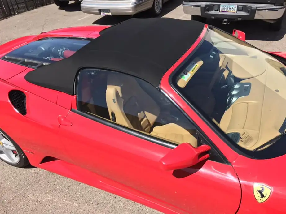 A red Ferrari with a new black convertible top and tan interior.