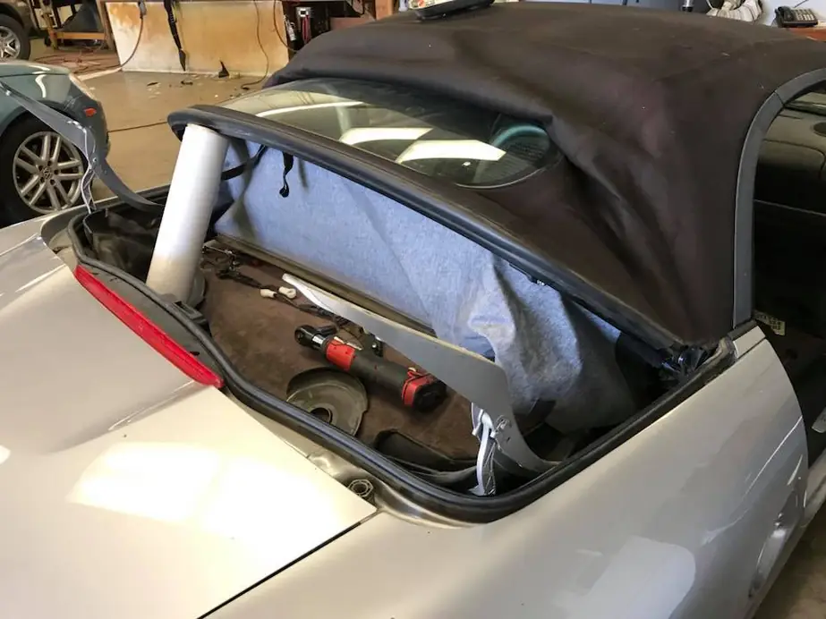 Silver convertible mid-repair with the top frame and bows exposed