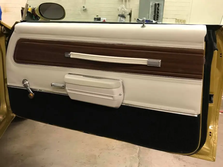 A classic door panel, white vinyl with a woodgrain insert and chrome pull.