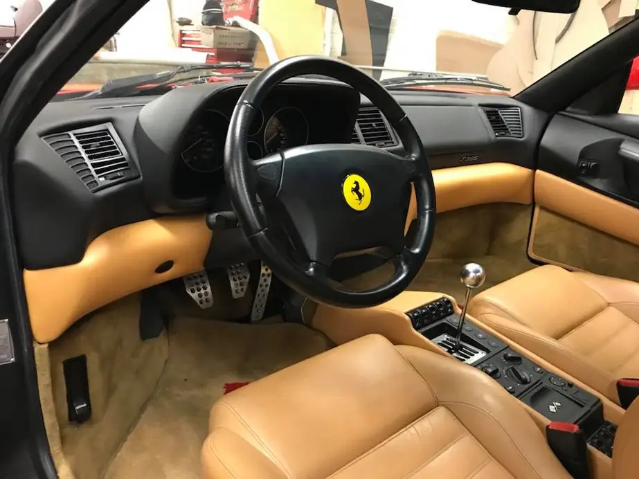 A Ferrari interior with tan leather seats and console.