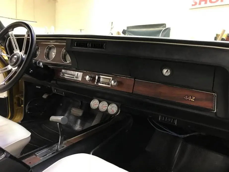 A classic dash with a woodgrain fascia, the 442 badge legible.
