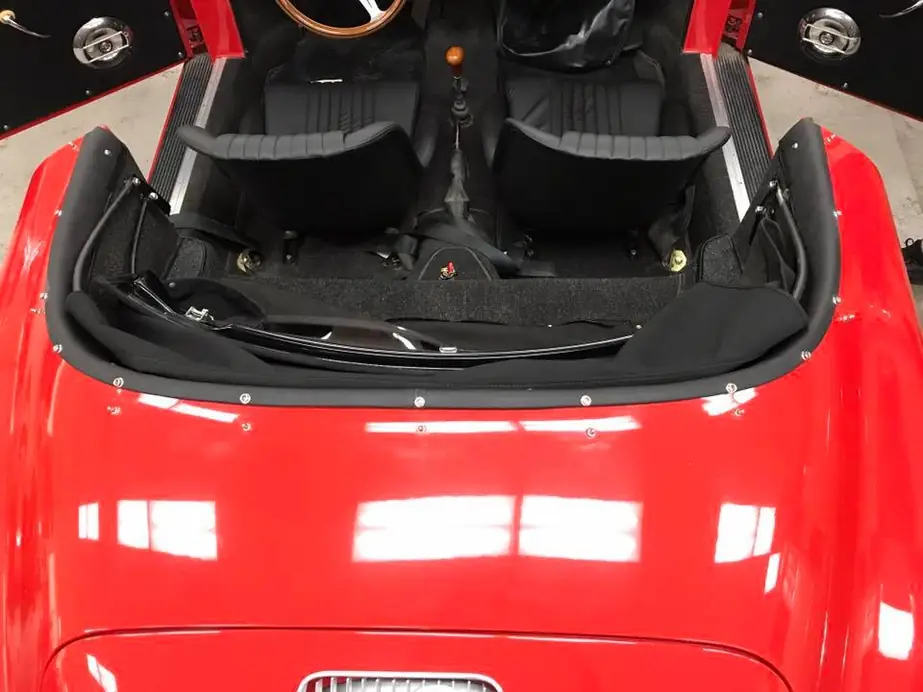 A red roadster from the rear, black interior, top stowed.