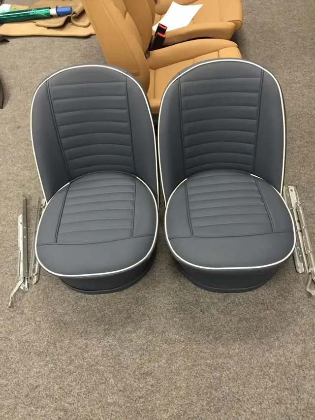 A pair of classic sports-car bucket seats in grey with white piping.